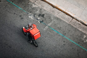 A young man working for a food delivery service, riding bike